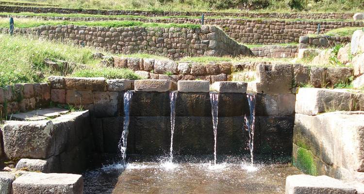 Les canaux d'irrigation en pierre anciens des Incas à Tambomachay avec une eau claire en cascade dans des bassins rectangulaires.