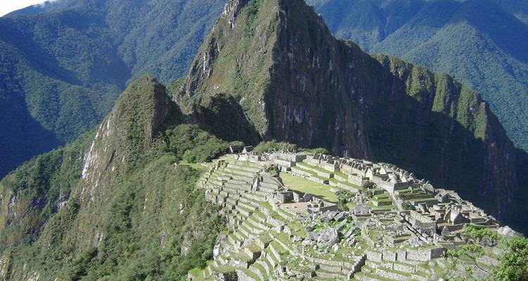 Vue aérienne panoramique des ruines en terrasses du Machu Picchu s'étendant sur une crête montagneuse verdoyante.