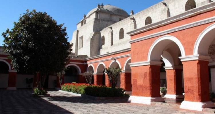 Colorful arches and flower-filled courtyard of the Santa Catalina Monastery under a clear blue sky.
