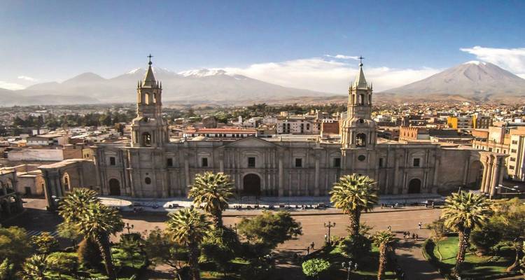 Aerial panorama of Arequipa’s main cathedral with snow-capped volcanoes rising behind the city.