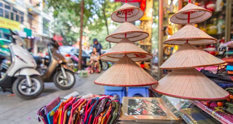 Exposition de chapeaux coniques traditionnels à vendre dans un marché de rue animé du Vietnam.