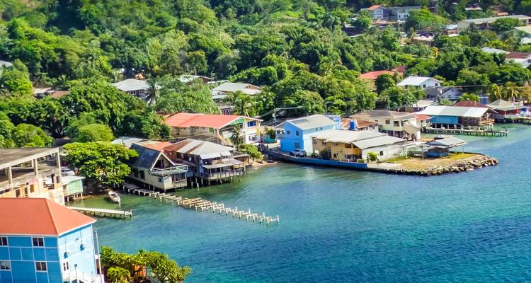 Colorful waterfront village with stilt houses overlooking clear turquoise Caribbean water