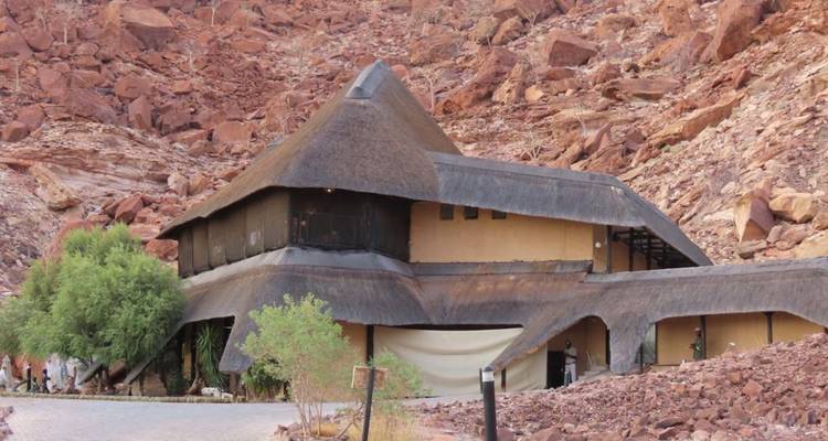 Traditionelle Hütte mit Strohdach in felsiger Landschaft.