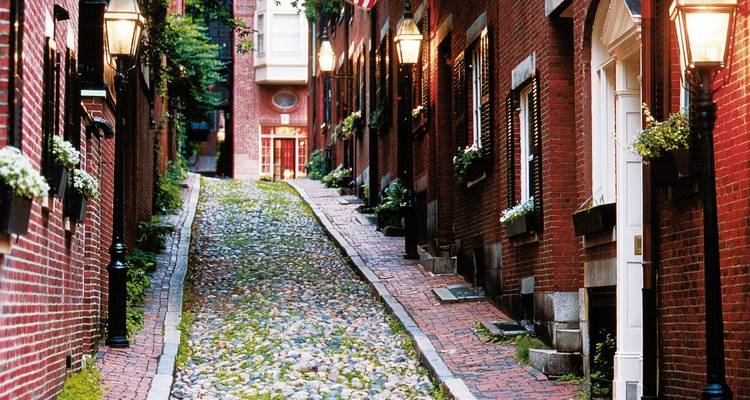 Quaint narrow cobblestone lane lined with historic red-brick houses and glowing lanterns.