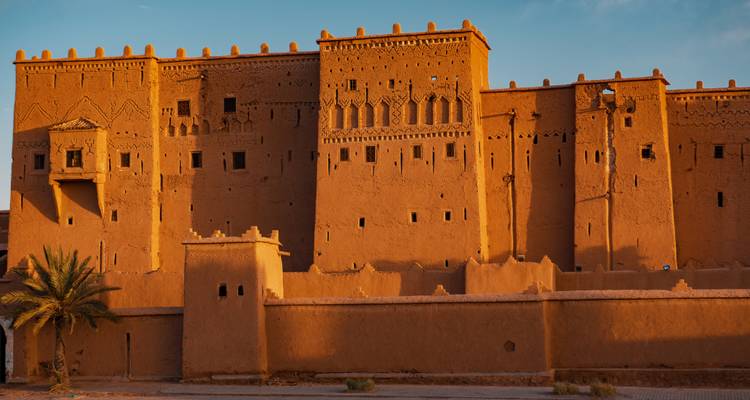 Les imposants murs en terre crue fortifiée d'une kasbah marocaine mis en évidence par la lumière chaude du coucher de soleil
