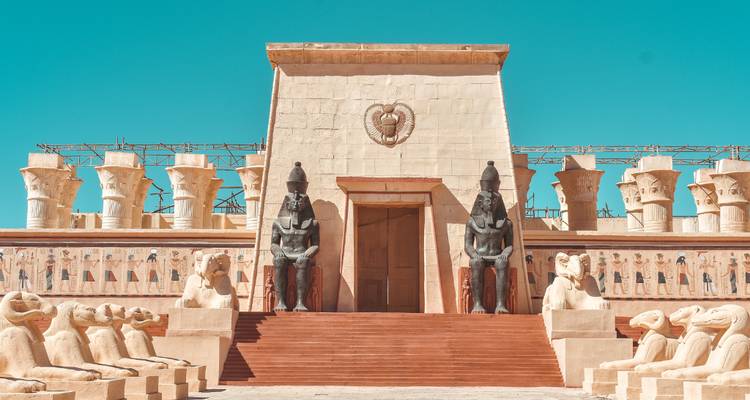 Plateau de tournage sur le thème de l'Égypte ancienne avec portail monumental flanqué de statues assises sur un ciel turquoise
