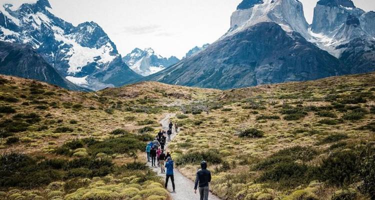 El grupo de trekking sigue un sendero sinuoso hacia los picos nevados y escarpados de Torres del Paine.