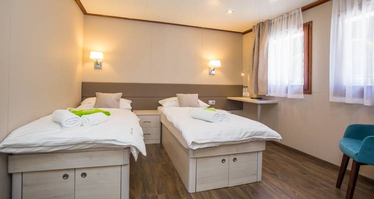 Camas individuales en una cabaña con cortinas y suelo de madera.