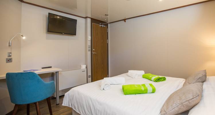 Interior de una cabina de yate con una cama y comodidades modernas.