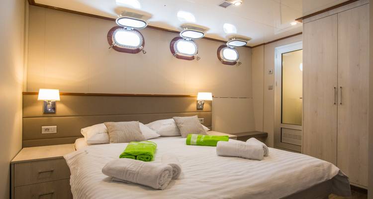 Camarote de cama doble con ojos de buey en un yate.