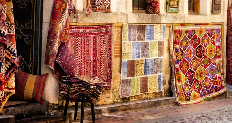 Bunte orientalische Teppiche, die auf einer Kopfsteinpflasterstraße ausgestellt sind.