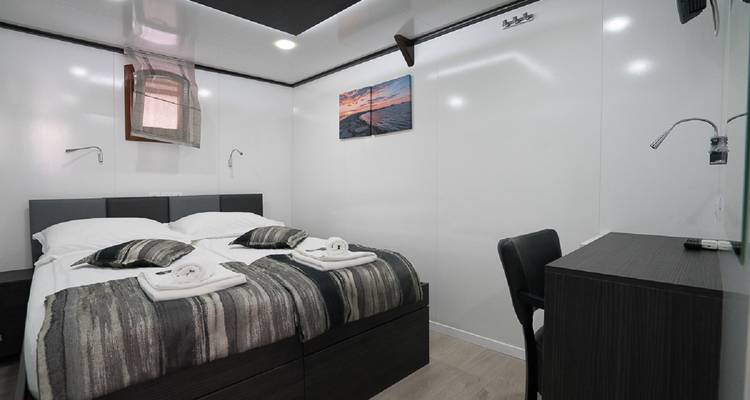 Innenraum einer Yachtkabine mit Doppelbett und nautischem Thema.