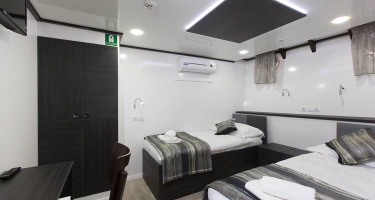 Yachtkabineninterieur mit zwei Einzelbetten und eleganter Dekoration.