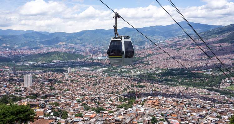 Zwevende kabelbaan boven het uitgestrekte stadsgezicht en bergdal van Medellin