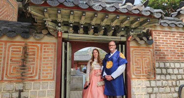 Zwei Personen in traditioneller Kleidung vor einem Tor im koreanischen Stil.