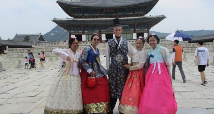 Gruppe von Menschen in traditioneller koreanischer Kleidung an einer historischen Stätte.