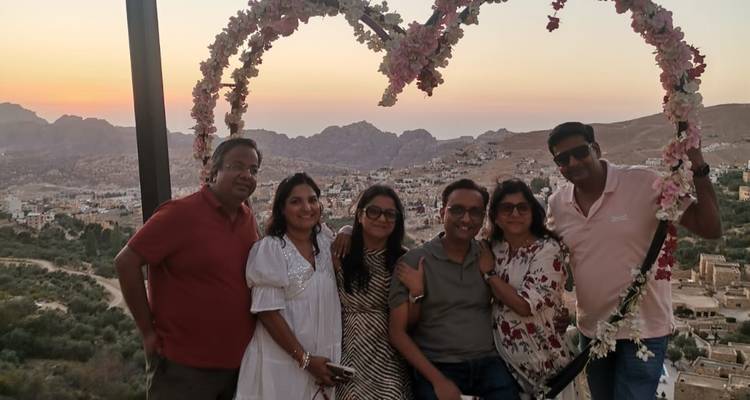Groupe posant sous une structure décorative en forme de cœur avec des montagnes en arrière-plan.
