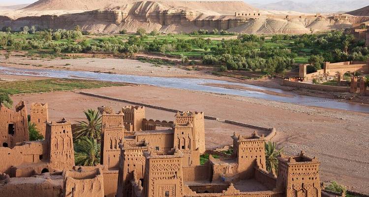 Paysage désertique avec structures en adobe et une rivière.