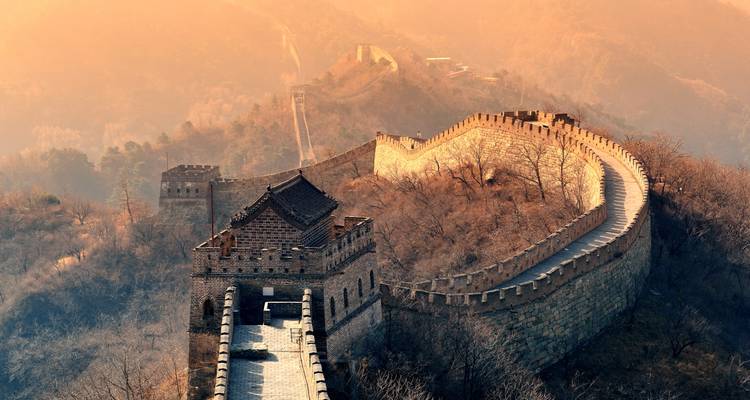 The Great Wall of China stretching across a hilly landscape during sunset.