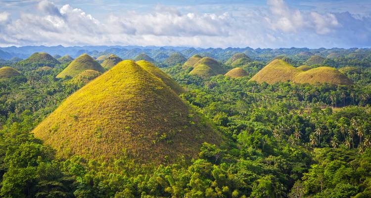 Malerische Aussicht auf die Chocolate Hills unter einem blauen Himmel mit Wolken.