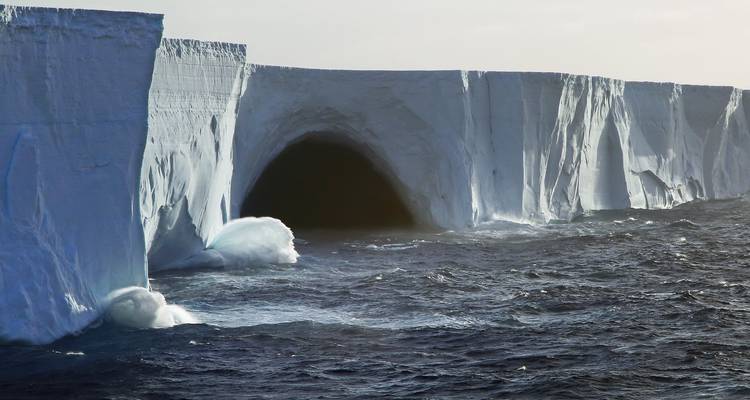 D'énormes icebergs avec des vagues qui s'écrasent contre eux dans une mer houleuse.