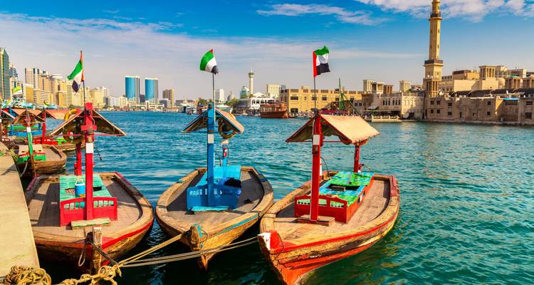 Bunte Boote am Bach vertäut mit einer Stadtsilhouette im Hintergrund.