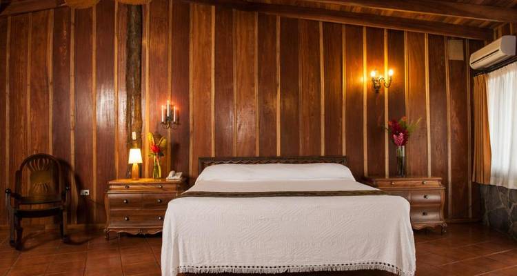 Habitación de hotel con paneles de madera, muebles elegantes e iluminación tenue.