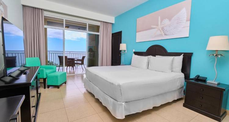 Habitación de hotel junto al mar con decoración vibrante y vista al balcón.