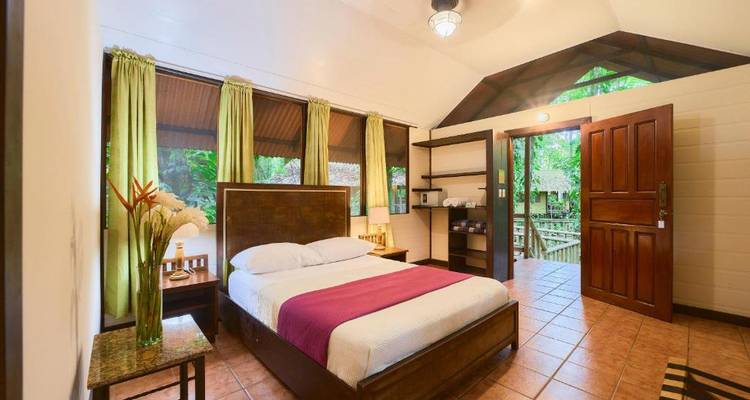 Una cómoda habitación de hotel con una cama y una puerta abierta que conduce a una terraza.