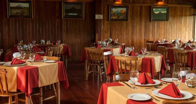 Un área de comedor acogedora con varias mesas preparadas para los huéspedes.