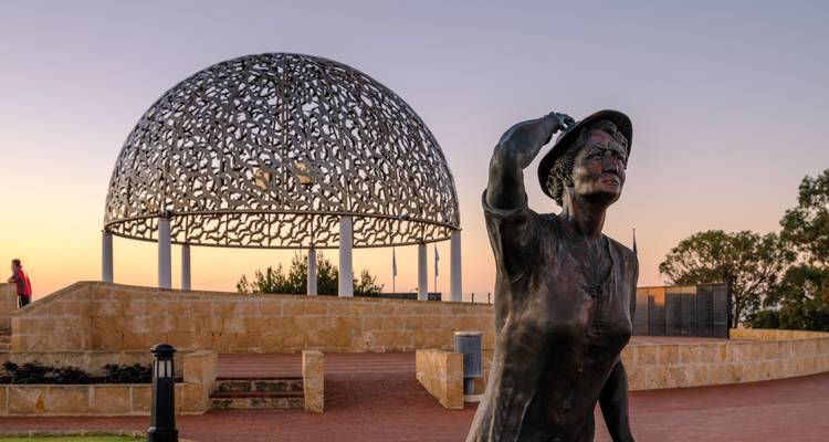 Statue vor einer Kuppelstruktur mit Sonnenuntergangslicht.