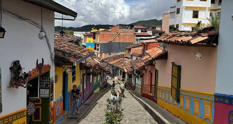 Rue étroite et colorée de Guatapé bordée de murales, avec des habitants et des touristes se promenant dans la ruelle pavée.