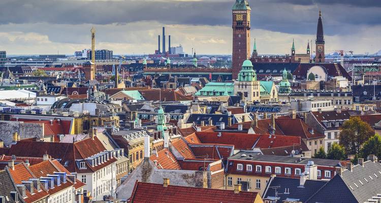 La silhouette de Copenhague avec ses tours en brique, ses clochers et ses toits rouges sous un ciel nuageux.
