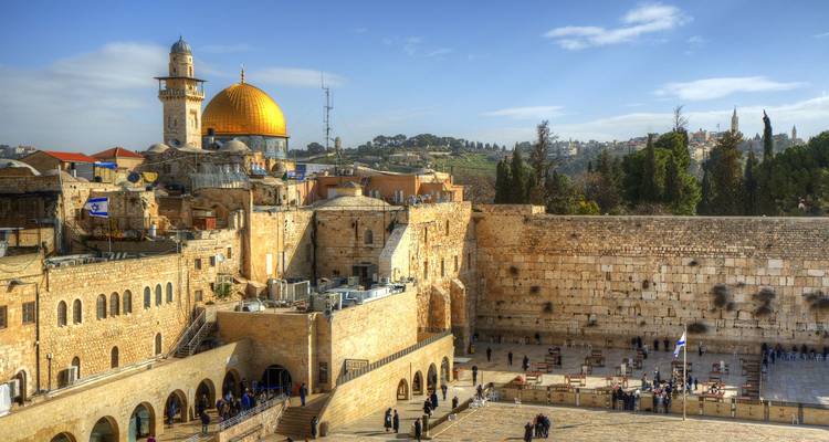 Sacred Western Wall with golden Dome of the Rock rising above historic Jerusalem skyline.