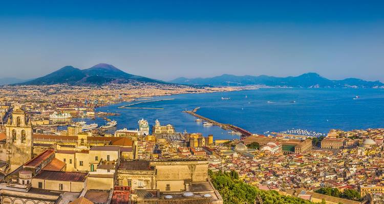 Panorama aéreo expansivo de la bahía y la ciudad de Nápoles con el Monte Vesubio dominando el horizonte.