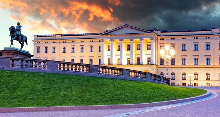 Der Königliche Palast von Oslo leuchtet unter dramatischen Sonnenuntergangswolken über einem gepflegten Rasen.