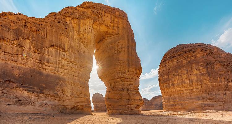 Rock formations in a desert landscape with sunlight peeking through.