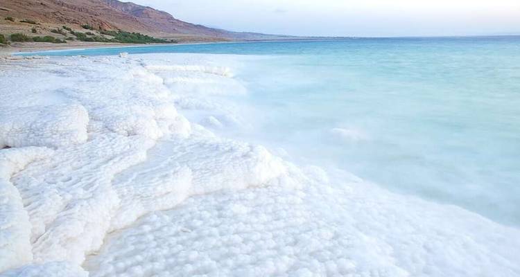 Formations de sel sur la rive de la mer Morte avec de l'eau bleue.