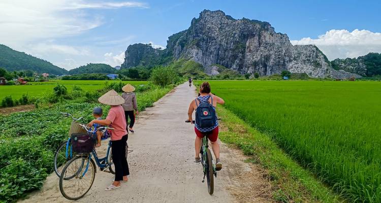 Frauen, die Fahrrad fahren und zu Fuß gehen, mit Bergen im Hintergrund.