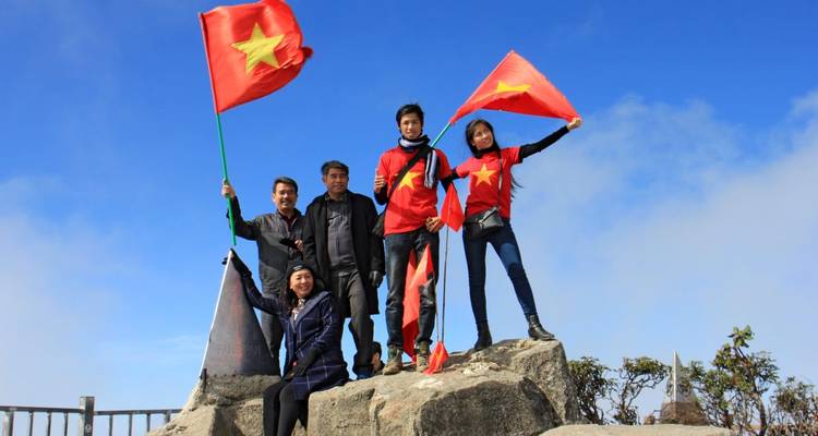 Gruppe von Menschen, die mit vietnamesischen Flaggen auf einem Gipfel posieren.
