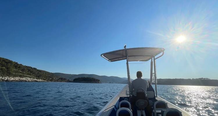 Homme dirigeant un bateau sur l'eau libre sous un ciel bleu dégagé.