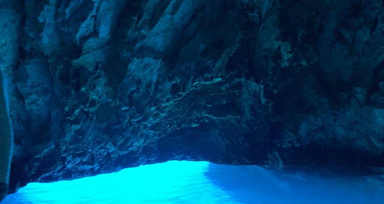 Grotte avec eau bleue illuminée à l'intérieur.
