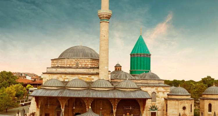 Complexe du musée historique Mevlana dans la lumière chaude du soir, présentant son dôme turquoise distinctif et son minaret.