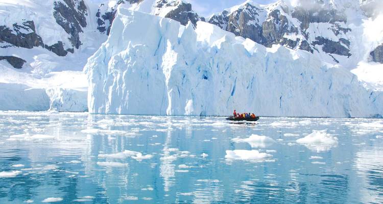 Large icebergs in Antarctica with a small boat of tourists.