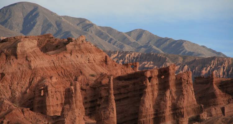 Dramatische rode rotsformaties met bergen in de verte.