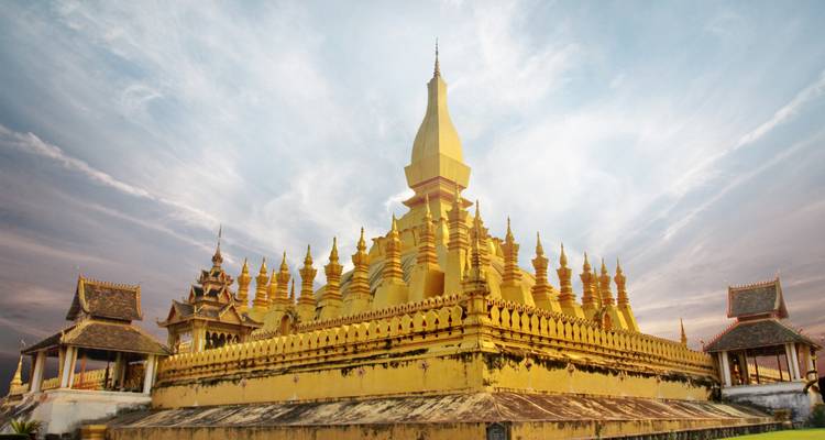 Un grand stupa doré aux détails complexes se détachant sur un ciel dramatique.