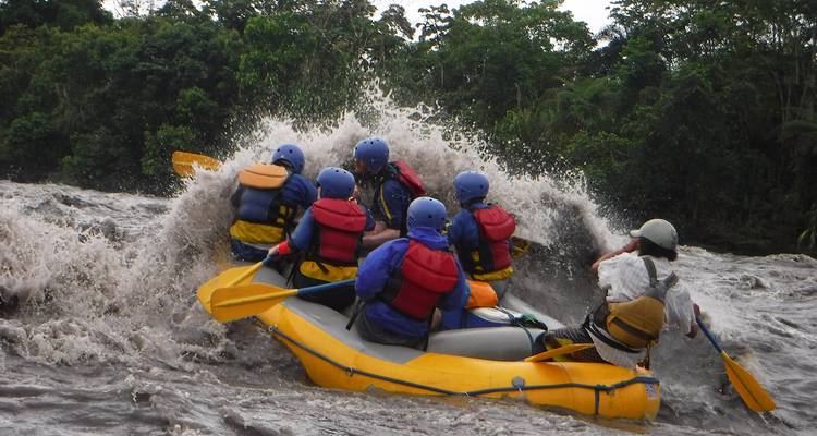 Gruppe von Menschen beim Wildwasser-Rafting auf einem turbulenten Fluss.