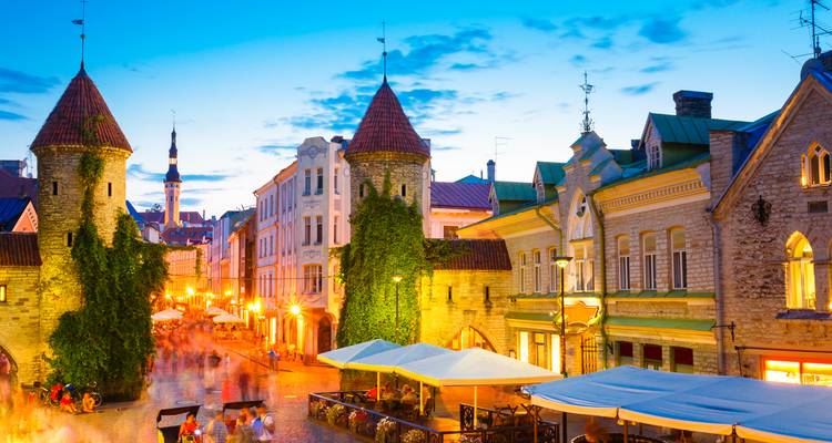 Les lumières du soir brillent le long de la porte Viru de Tallinn et des rues pavées avec des foules floues.