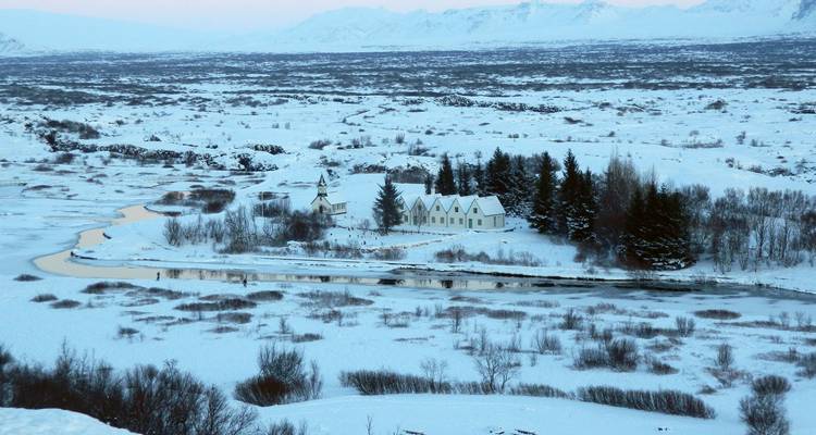 Sneeuwbedekt landschap en klein kerkje naast een slingerende rivier in Nationaal Park Thingvellir