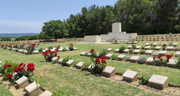 War cemetery with rows of graves and red flowers.